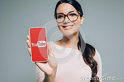 beautiful smiling girl presenting smartphone with youtube appliance Editorial Stock Photo