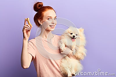 Beautiful smiling red-haired girl holding adorable pet and bone Stock Photo
