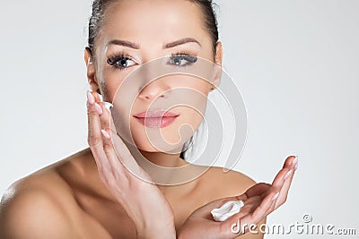 Beautiful smiling woman applying cream on face Stock Photo