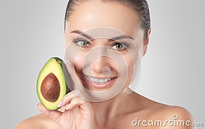 Beautiful smiling woman with clean skin holds ripe avocado near the face. Cosmetology skin care Stock Photo