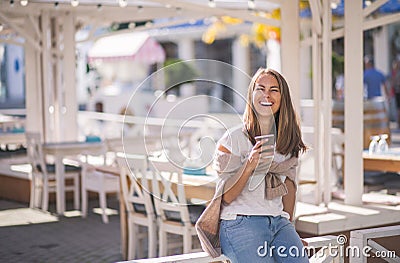 Beautiful woman holding paper coffee cup and enjoying the walk in the city Stock Photo