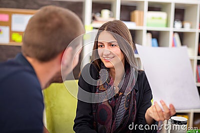 Beautiful smiling young businesswoman sitting working with a young man in a busy office Stock Photo