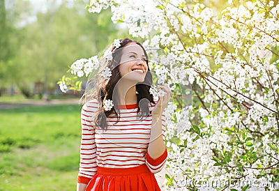 Beautiful smiling young woman enjoying smell flowering spring Stock Photo