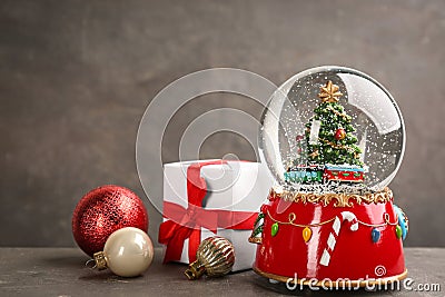 Beautiful snow globe, gift box and Christmas balls on grey table Stock Photo