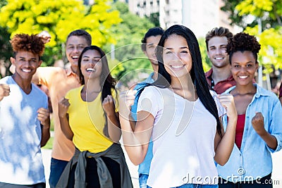 Beautiful south american female student with group of cheering young adults Stock Photo