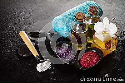 Beautiful Spa Set Spa Products with Essential Oils, Soap, Towel, Spa Sea Salt on Dark Wet Background. Horizontal Stock Photo