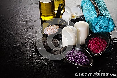 Beautiful Spa Set Spa Products with Essential Oils, Soap, Towel, Spa Sea Salt on Dark Wet Background. Horizontal with Copy Space. Stock Photo