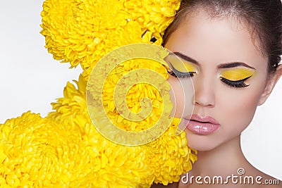 Beautiful Spa Woman over chrysanthemum flowers. Eyes makeup. Beauty Portrait. Perfect Fresh Skin. Pure Beauty Model Girl. Stock Photo