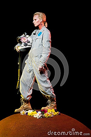 beautiful spacewoman in spacesuit with flowers and helmet standing on red Stock Photo
