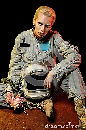 beautiful spacewoman in spacesuit with helmet and flower sitting Stock Photo