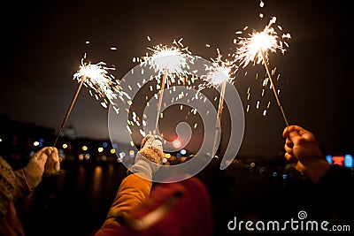 Beautiful sparklers in woman hands on dark background Stock Photo