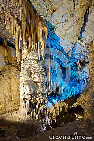 Beautiful speleothem stalagnata, stalactites, stalagmites in natural cave illuminated by color lights Stock Photo