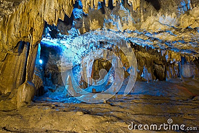 Beautiful speleothem stalagnata, stalactites, stalagmites in natural cave illuminated by color lights Stock Photo