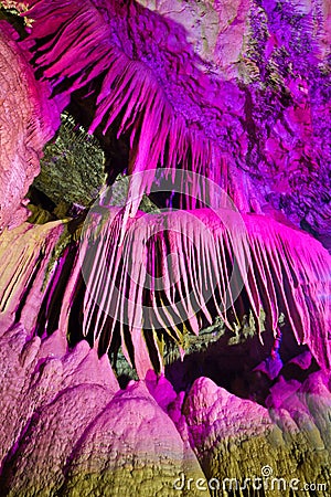 Beautiful speleothem stalagnata, stalactites, stalagmites in natural cave illuminated by color lights Stock Photo