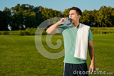 Beautiful sportsman drinking water on the lawn. Stock Photo