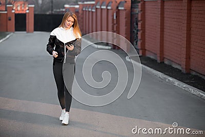 Beautiful sporty girl using device walking in the street Stock Photo