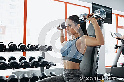 Beautiful sporty woman doing power fitness exercise at sport gym. Stock Photo
