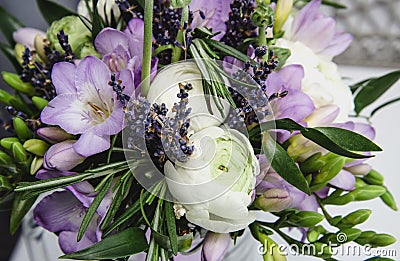 Beautiful spring bouquet wedding flowers buttercup ranunculus, fresia, lavender nature background. Pastel colors purple