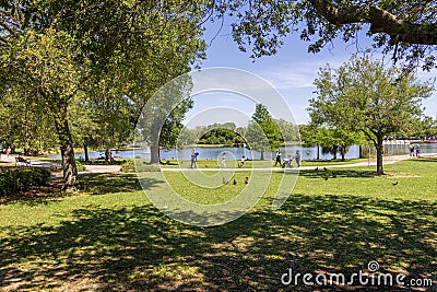 A beautiful spring landscape at New Orleans City Park with people, lush green trees, grass and plants, a lake, birds and blue sky Editorial Stock Photo