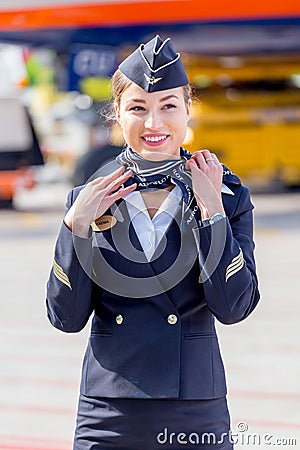 Beautiful stewardess dressed in official dark blue uniform of Aeroflot Airlines on airfield. Passenger jet aircraft on background. Editorial Stock Photo
