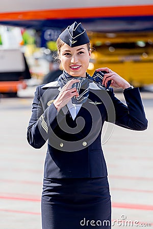 Beautiful stewardess dressed in official dark blue uniform of Aeroflot Airlines on airfield. Passenger jet aircraft on background. Editorial Stock Photo