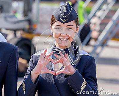 Beautiful stewardess dressed in official dark blue uniform of Aeroflot Airlines on airfield. Passenger jet aircraft on background. Editorial Stock Photo