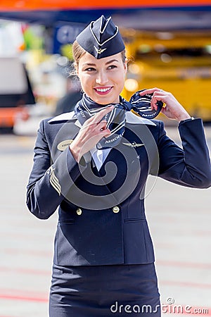 Beautiful stewardess dressed in official dark blue uniform of Aeroflot Airlines on airfield. Passenger jet aircraft on background. Editorial Stock Photo