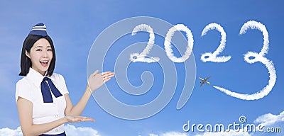 Beautiful stewardess showing the 2023 travel concept on blue background Stock Photo