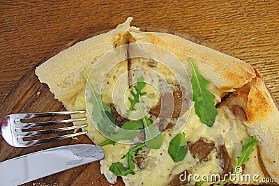 Still life on the table in a cafe with pizza on a wooden Board and a fork with a knife Stock Photo