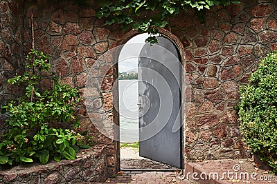 In the beautiful stone wall the iron door is ajar Stock Photo