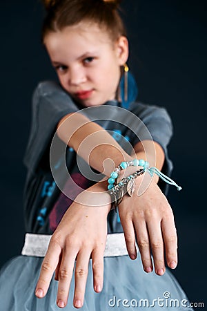 A beautiful and stylish bracelet made of blue beads and feathers on the hand of a teenage girl. Stock Photo