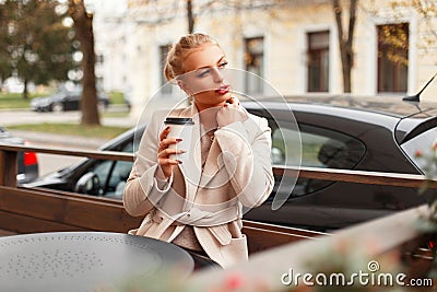 Beautiful stylish young woman in a coat sits in a cafe Stock Photo