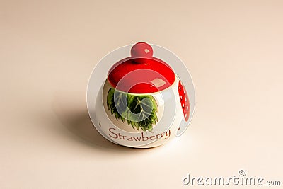 A beautiful sugar bowl with painted strawberries and a red lid, filled with white sugar on a white background Stock Photo