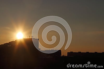 Beautiful sun during sunset over roofs of residential buildings Stock Photo