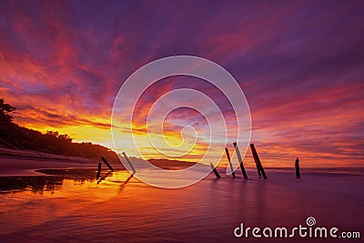 Beautiful sunrise of old jetty piles at St. Clair Beach in Dunedin, New Zealand Stock Photo