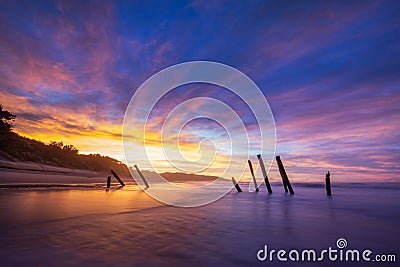 Beautiful sunrise of old jetty piles at St. Clair Beach in Dunedin, New Zealand Stock Photo