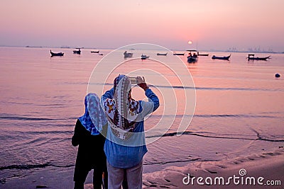 Beautiful sunrise. People enjoy the sunrise. Fishing boat silhouette with orange sunrise sky and water reflection Stock Photo