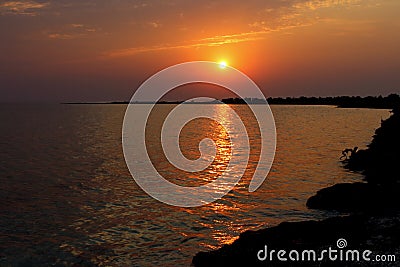 Beautiful sunrise on sea with golden reflection in water and seashore silhouette on horizon. Summer sea background. Vacation conce Stock Photo