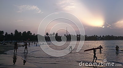 Beautiful sunset on the beach of Arugam Bay, kid with a surfboard, girls playing frisbee Editorial Stock Photo