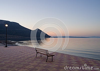 Beautiful sunset and bench on the seafront in Greece Stock Photo