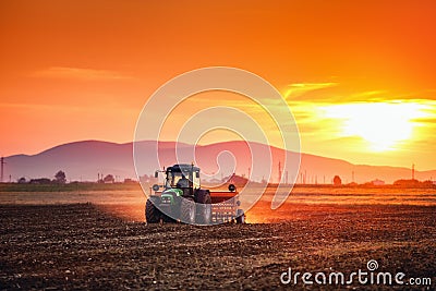 Beautiful sunset, farmer in tractor preparing land with seedbed Stock Photo