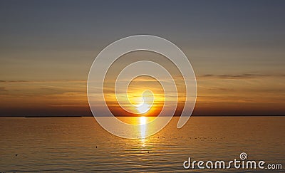 Beautiful sunset over the sea. The sun sets on the water. The sky is painted with bright colors. Sunset beach in a summer evening Stock Photo