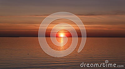 Beautiful sunset over the sea. The sun sets on the water. The sky is painted with bright colors. Sunset beach in a summer evening Stock Photo
