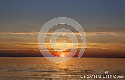 Beautiful sunset over the sea. The sun sets on the water. The sky is painted with bright colors. Sunset beach in a summer evening Stock Photo