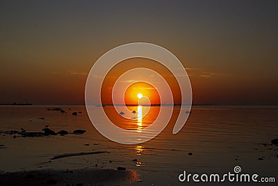 Beautiful sunset over the sea. The sun sets on the water. The sky is painted with bright colors. Sunset beach in a summer evening Stock Photo