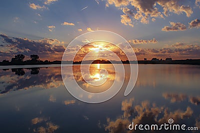 Blue and orange sunset reflected in Grundy County Lake Stock Photo
