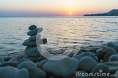 Beautiful sunset at sea and balancing pyramid of stones Stock Photo