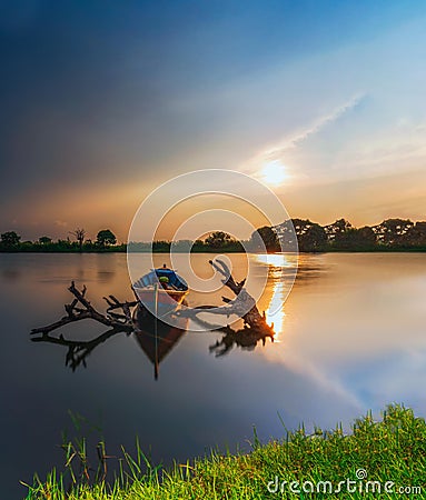 Beautiful sunset and traditional Beautiful little fishing boat with fantastic golden sky and nature Stock Photo