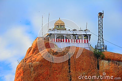 Beautiful sunset view of ancient Hindu Siva Temple at the top of barren rock against the background of cloudy blue sky in Trichy Stock Photo