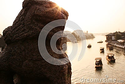 Beautiful sunset in Zhujiajiao ancient town, China. Traditional chinese lion sculpture, ships on water, river Stock Photo